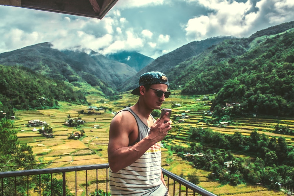 man in white tank top beside rail