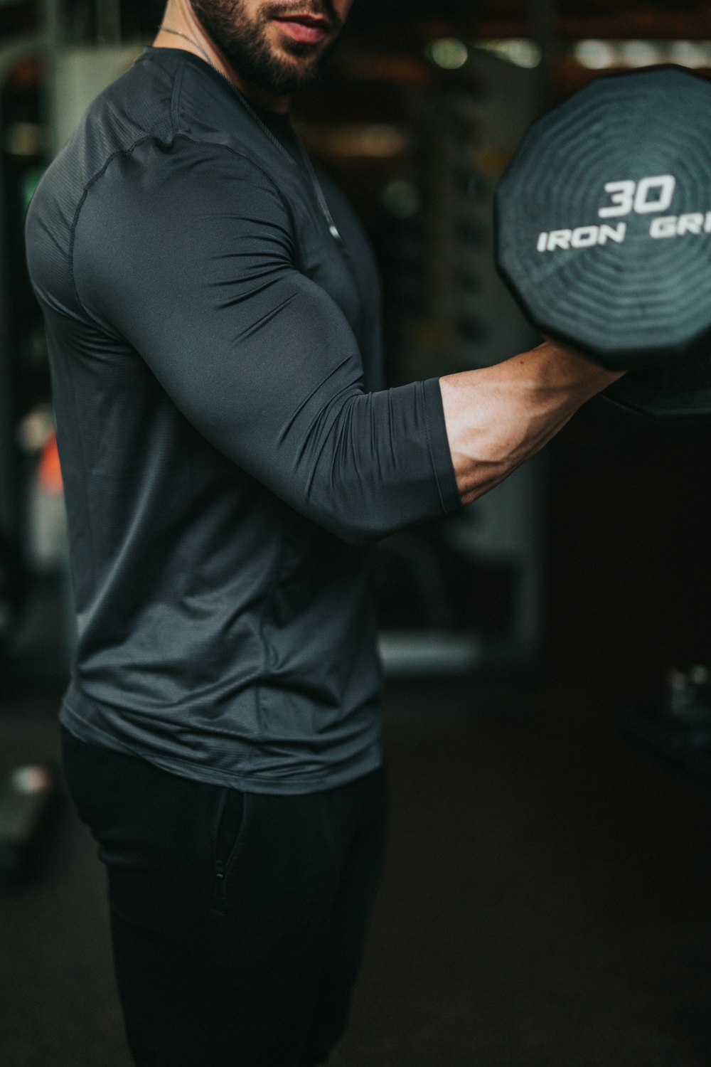 men's black long-sleeved shirt holding dumbbell