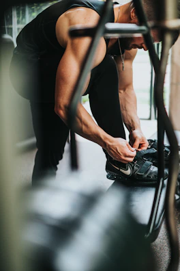 Athlete lacing up durable, cushioned training shoes on a gym floor.
