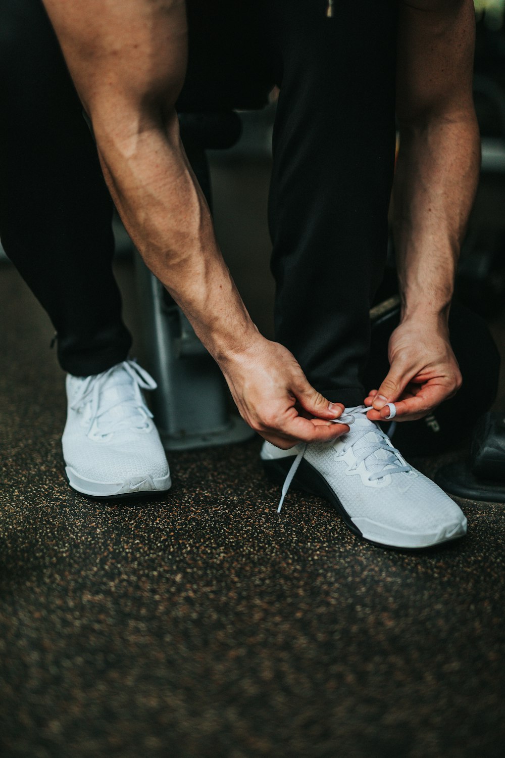 man sitting down while tying shoe lace