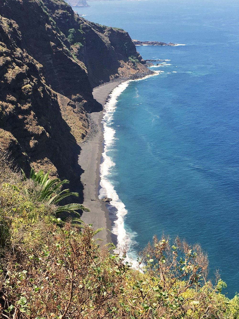 photography of mountain cliff beside seashore during daytime