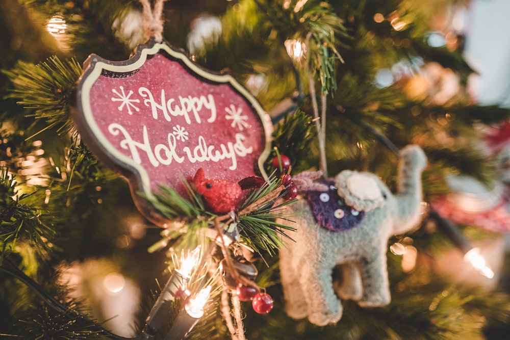 회색 코끼리 크리스마스 장식은 조명 크리스마스 트리에 매달려 있습니다.