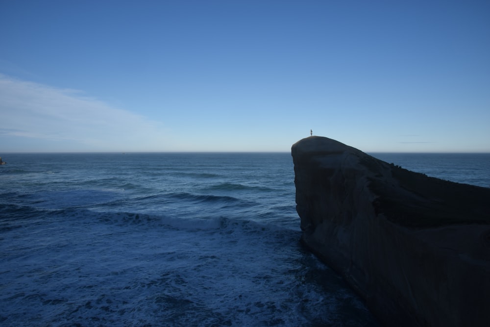 man standing on a mountain cliff fronting the sea