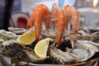Hand arranging a platter of fresh shellfish with lemon wedges and herbs.