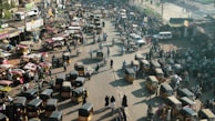 Bustling Delhi street with rickshaws and locals going about their day near India Gate.