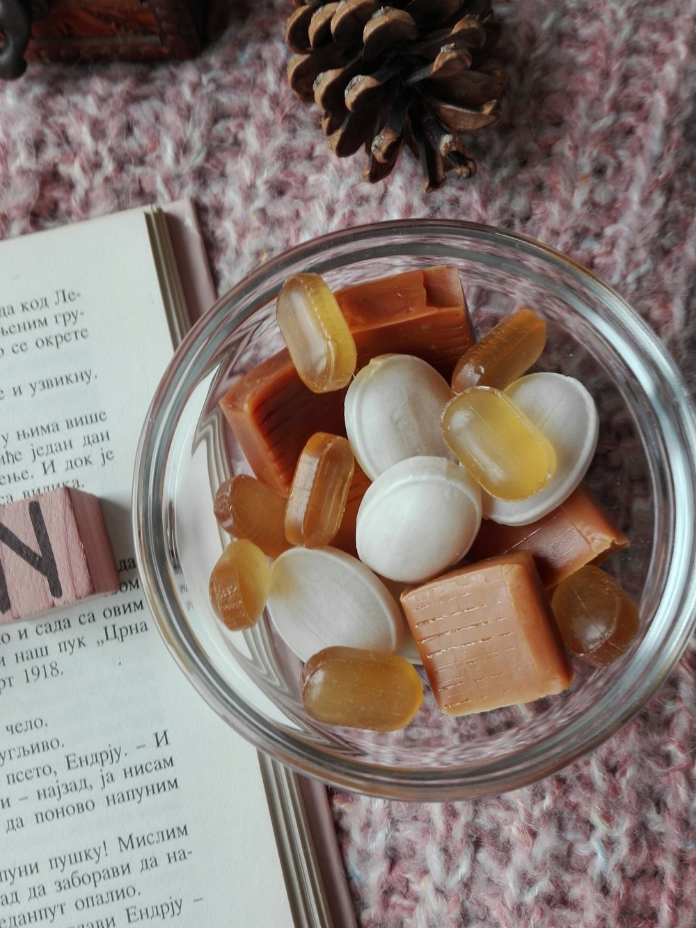 assorted candies in clear glass bowl beside book
