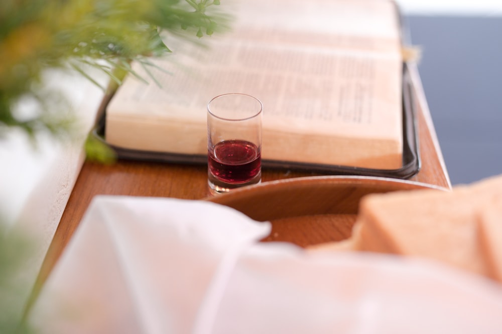 near empty drinking glass beside opened book