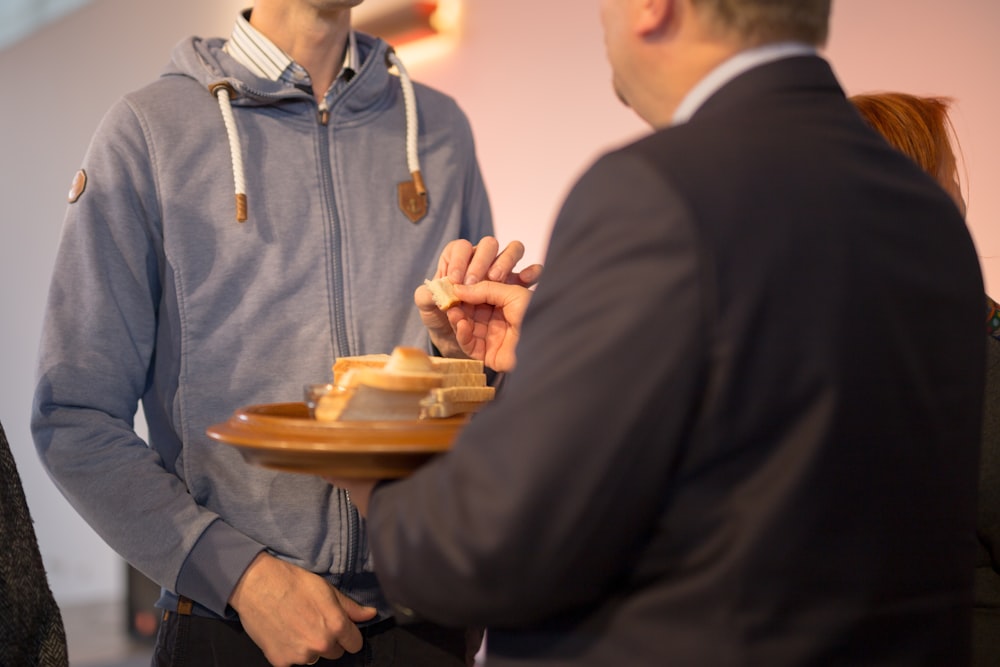 man holding tray with bread in front of man