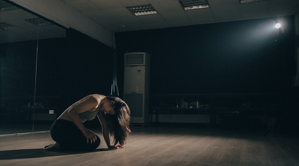 woman kneeling inside room near floor-type AC unit