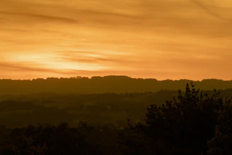 Sunset over rolling hills of the Axarquía with golden hues blending into the sky.