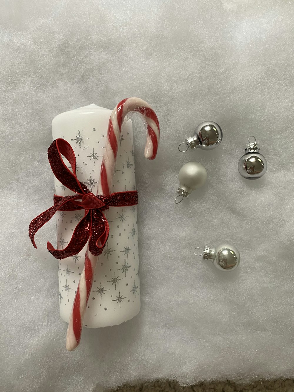 white pillar candle on beside baubles