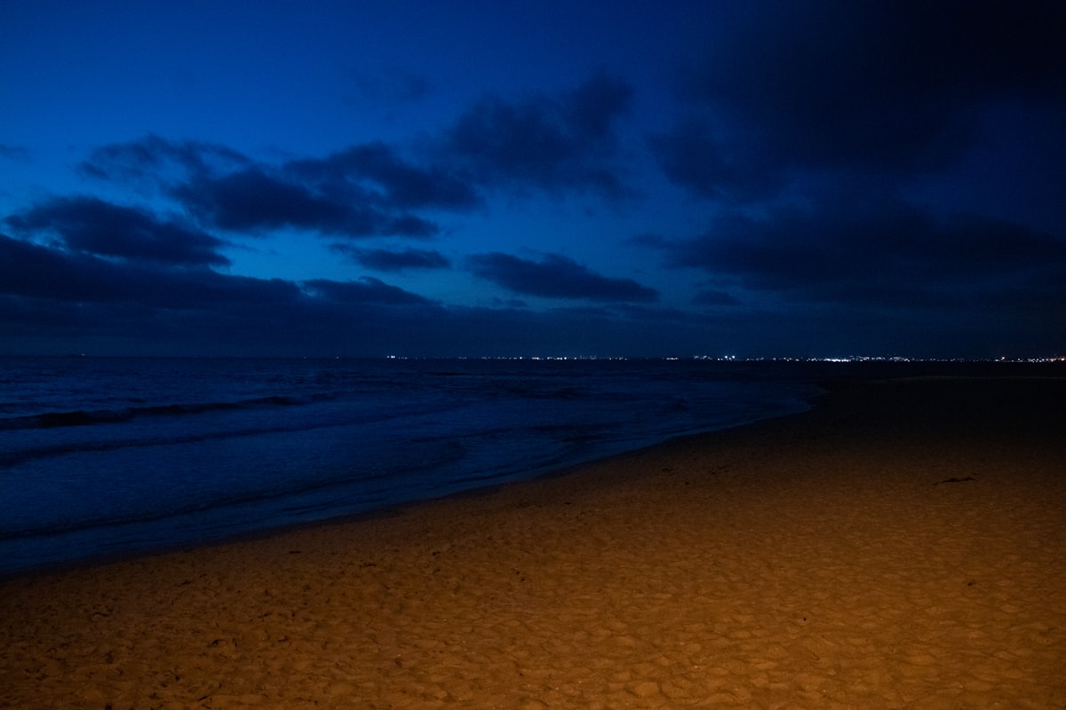 Calm ocean waters meeting the horizon under a brooding overcast sky at dawn