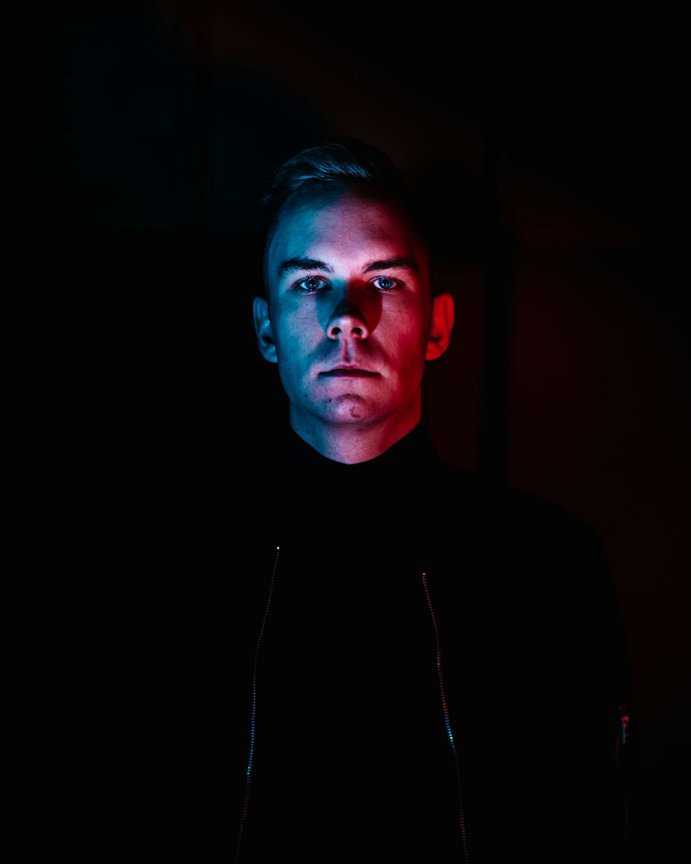 man in black jacket with red, white, and blue lights on his face