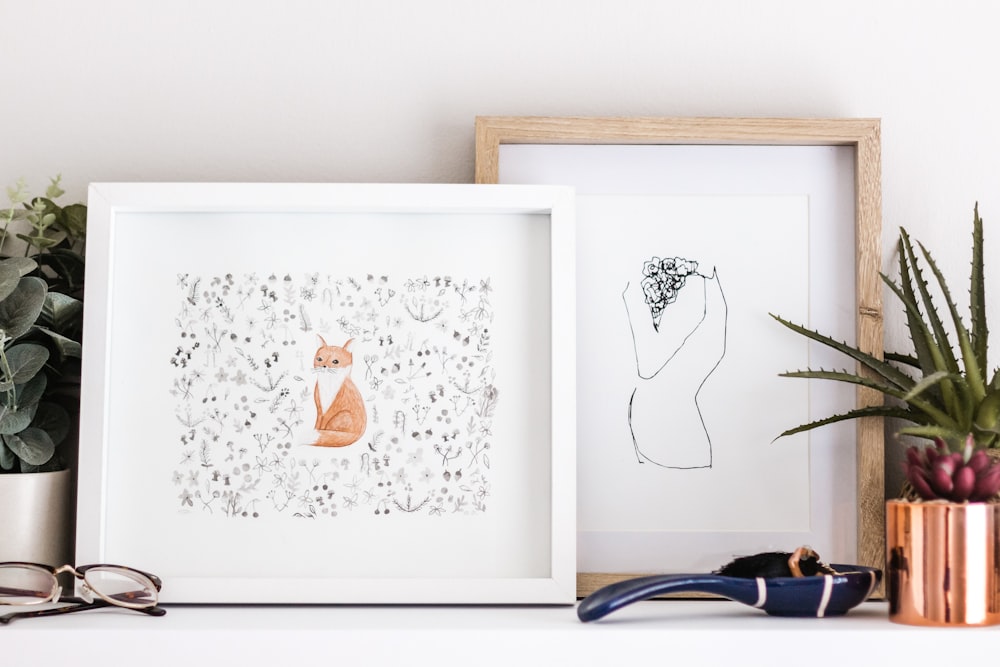 shallow focus photo of orange cat painting with white wooden frame