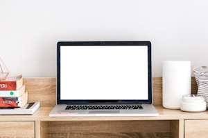 Stack of educational books and a laptop on a wooden desk.