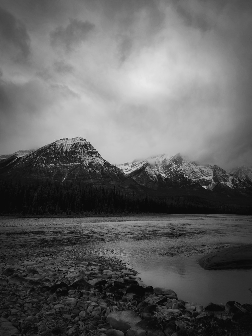 grayscale photography of lake by mountains