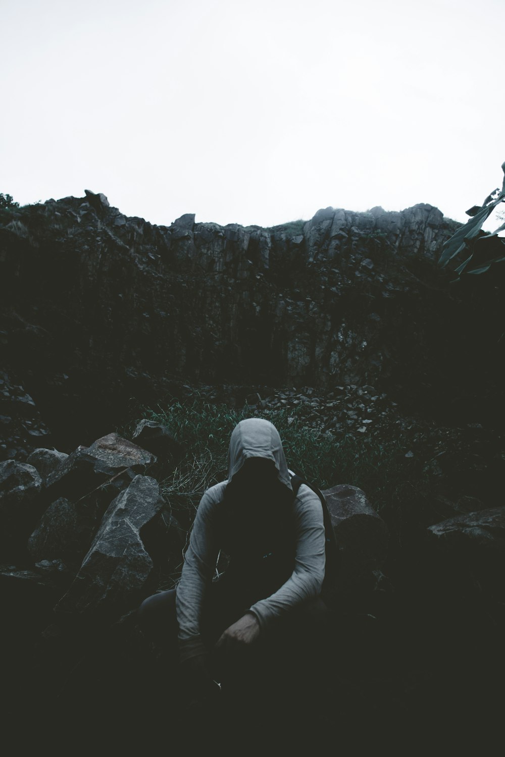 man wearing hoodie while sitting on ground