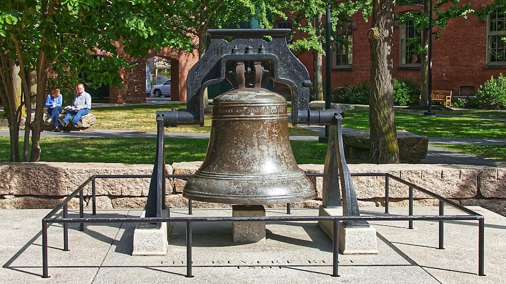a large metal bell sitting on top of a sidewalk