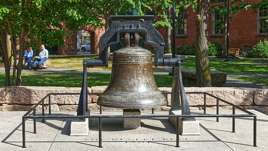 a large metal bell sitting on top of a sidewalk, Cette cloche est actuellement exposée dans un monument aux anciens comb