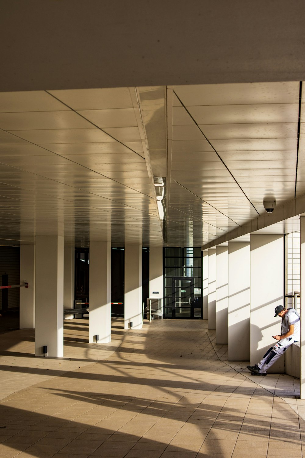 man sitting on railing beside pillars inside building