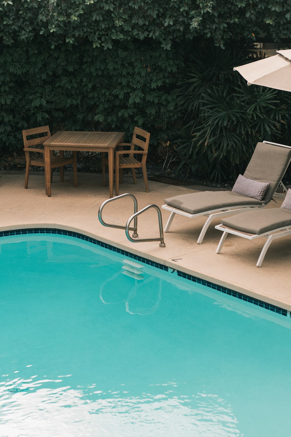 two gray sunbathing loungers beside pool