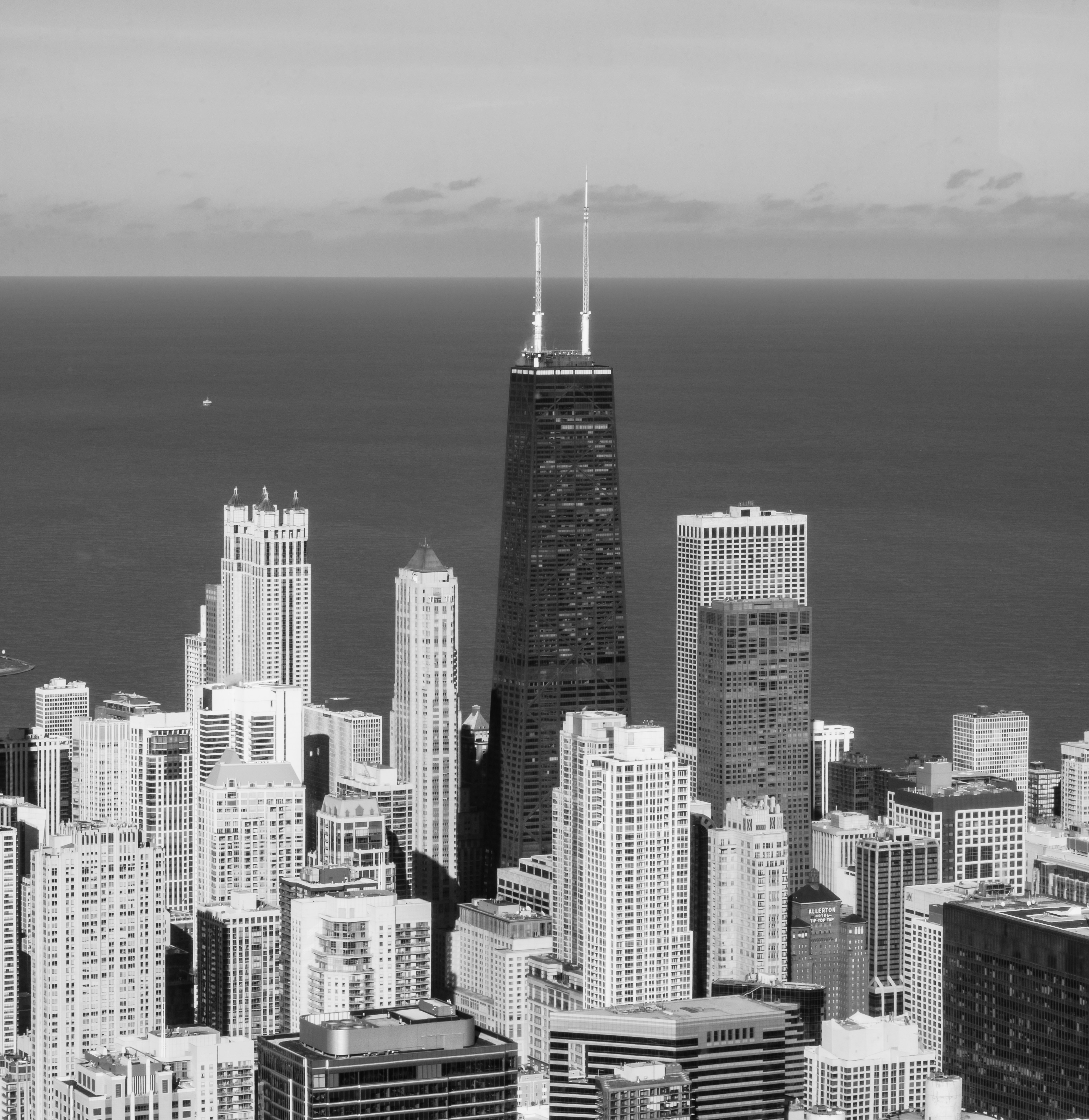 Black-and-white photograph of downtown Chicago with the Willis Tower centered among dense skyscrapers along the lake.