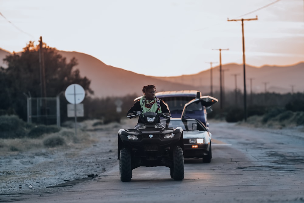 man riding on quad bike on road during daytime