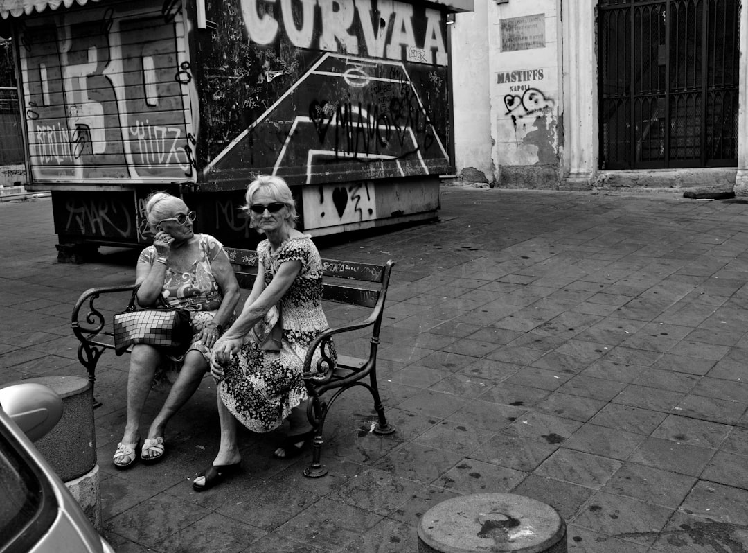 greyscale photo of two women sitting on outdoor