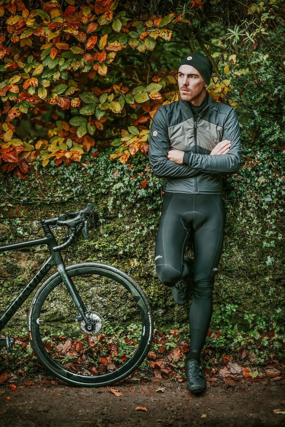 man leaning on bush wall beside bicycle