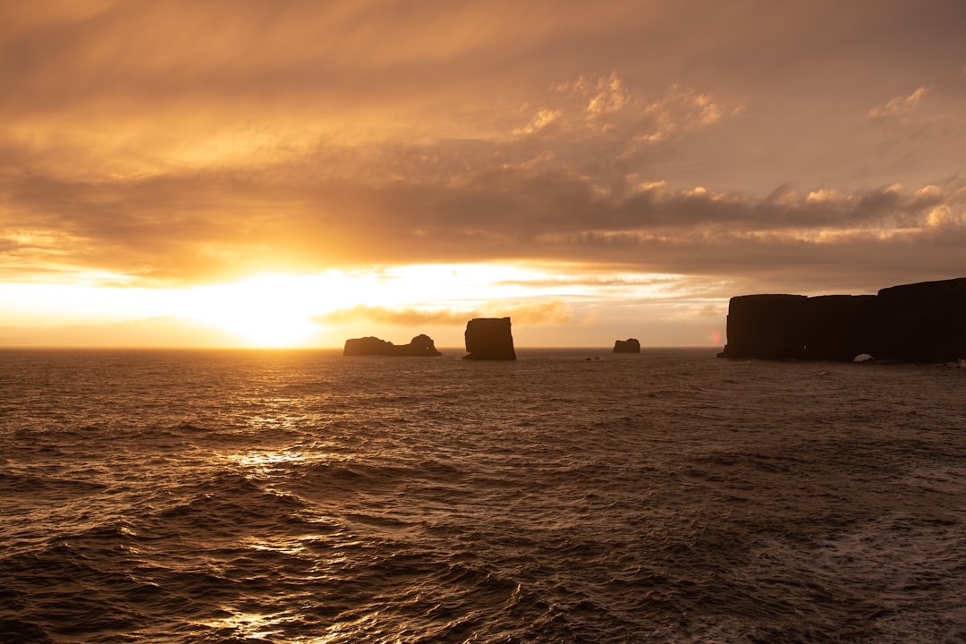 view photography of sea and stone cliff during dawn