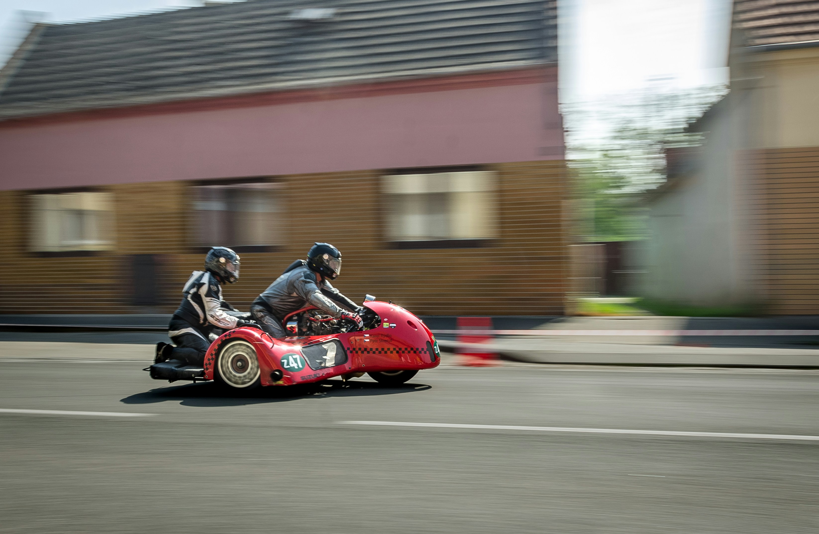 Panning photography of a red three-wheeled vehicle with two people riding