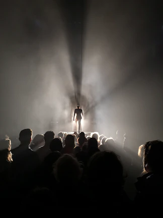 A proud teacher receiving an award on stage with a bright spotlight.