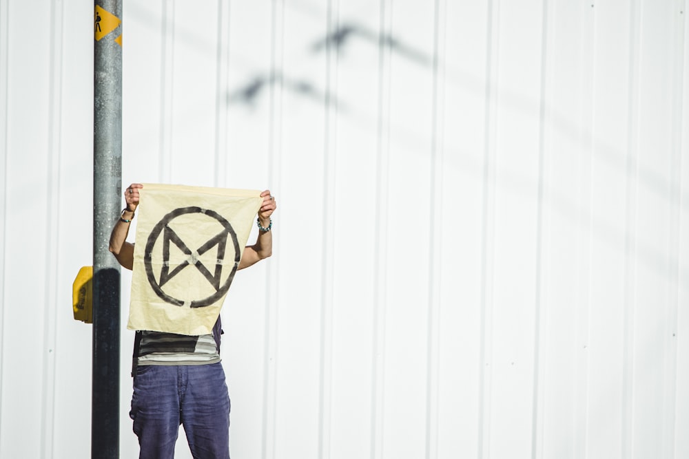 man holding banner standing beside metal post