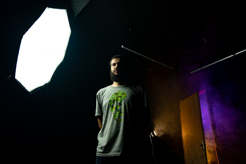 man in gray shirt standing near softbox