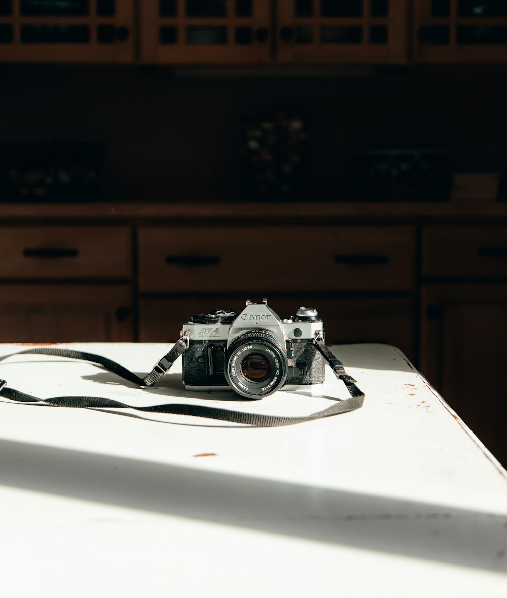 silver and black DSLR camera on white surface