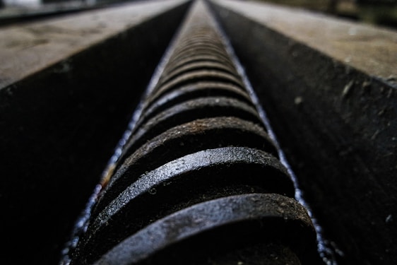 Close-up of a custom-made industrial screw being inspected by a technician in a modern factory setting.