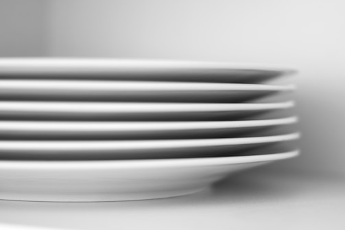 A set of abstract-designed plates stacked neatly with soft natural light.
