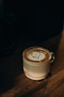 A creamy coffee latte with intricate latte art in a clear glass, sunlight highlighting the foam.