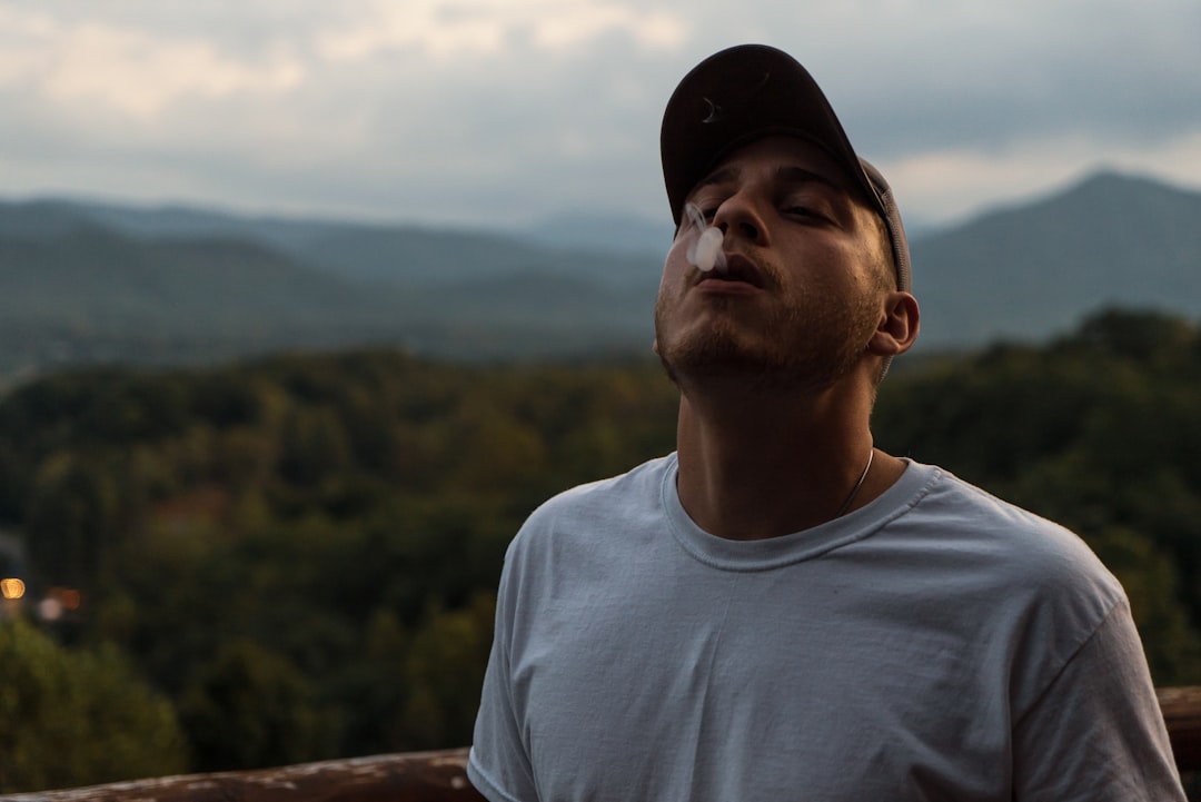 man in white crew-neck top smoking outdoors