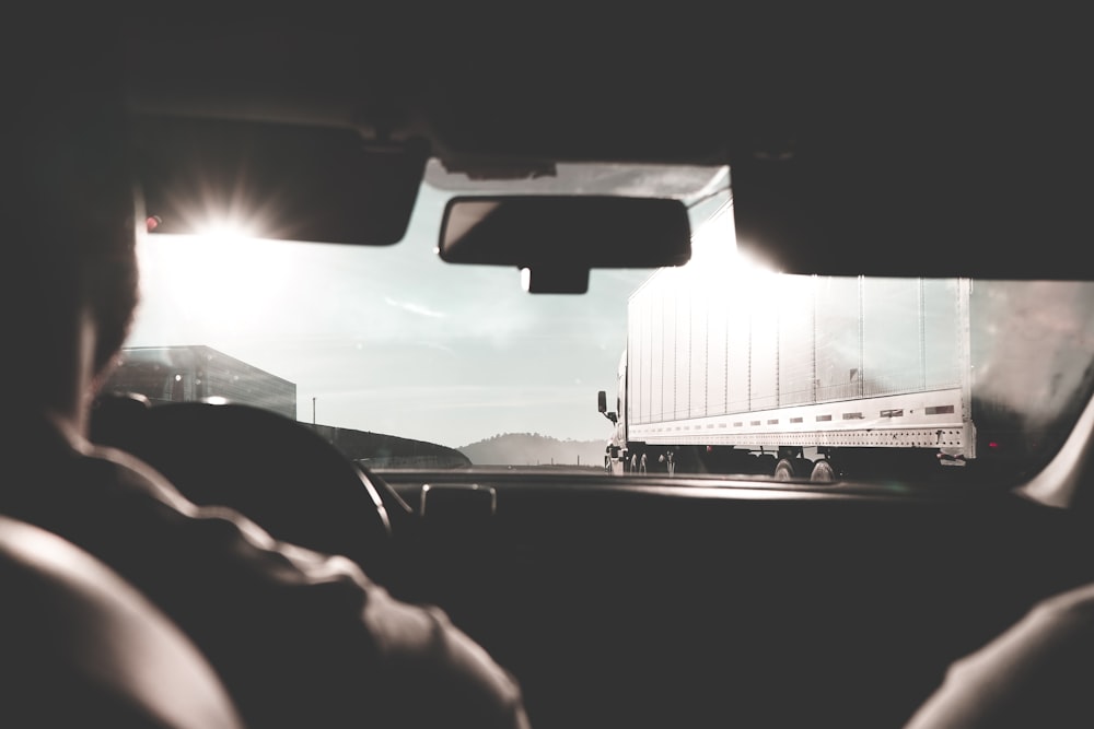 a person driving a car with a truck in the background