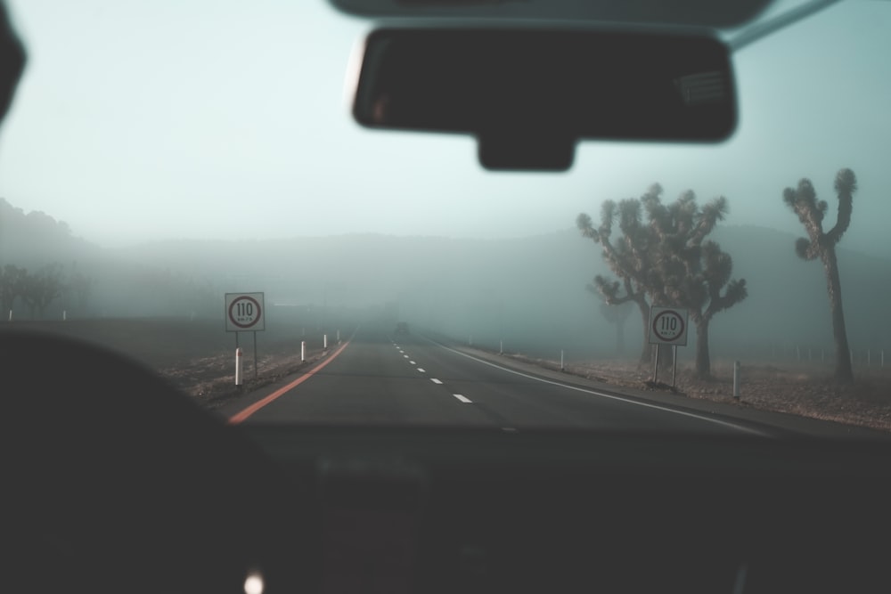 silhouette of vehicle dashboard and gray spahlt road