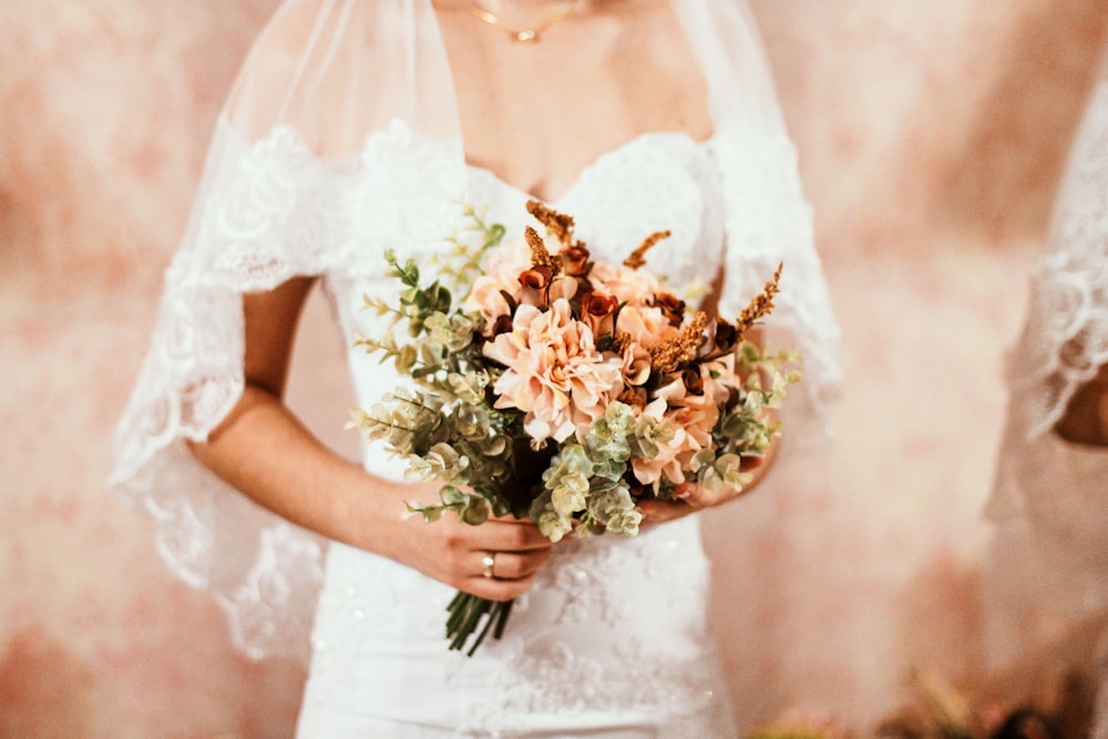 woman in white wedding dress holding bouquet of flower