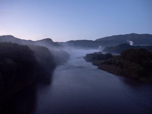 Serene Mechuka river winding through misty mountains at dawn.