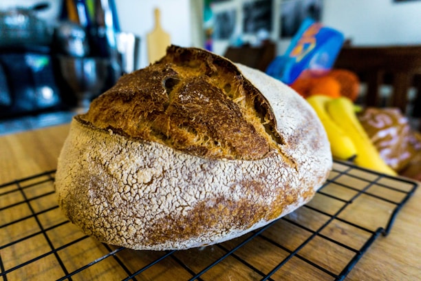 Close-up of golden brown artisan bread loaves cooling on a wooden rack.