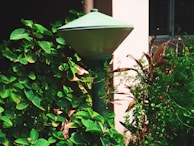 An outdoor wall lamp with sensor functionality in a garden.