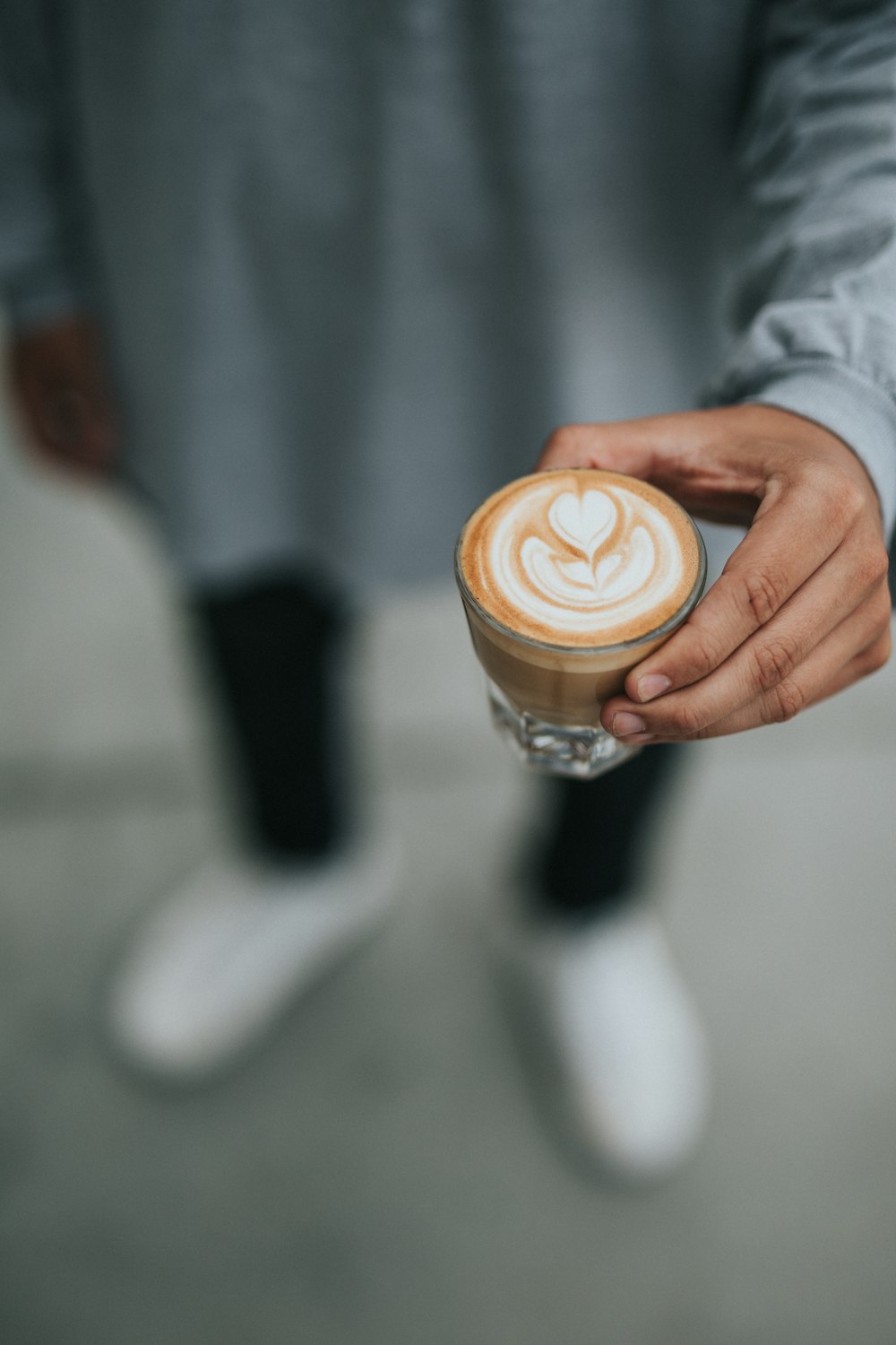 shallow focus photography unknown person standing holding cup of brown coffee