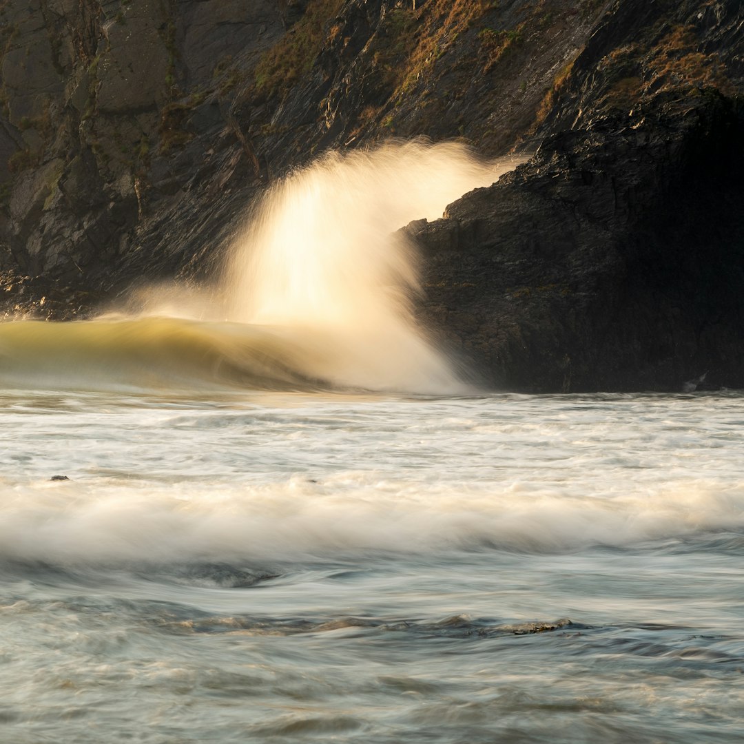view photography of sea wave on stone cliff