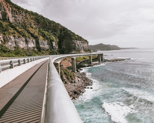 mountains near ocean under cloudy sky in Sea Cliff Bridge Australia