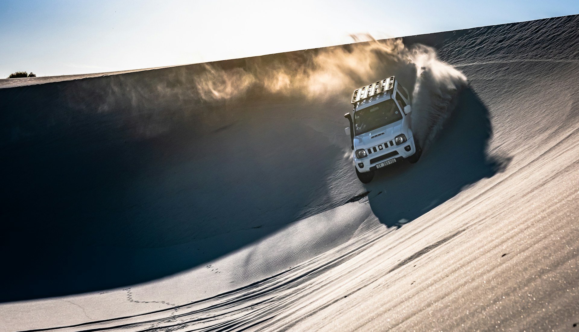Thrilling moment of a 4x4 vehicle speeding over sandy hills, kicking up clouds of dust.