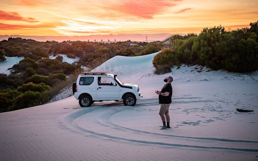 man on sand near vehicle